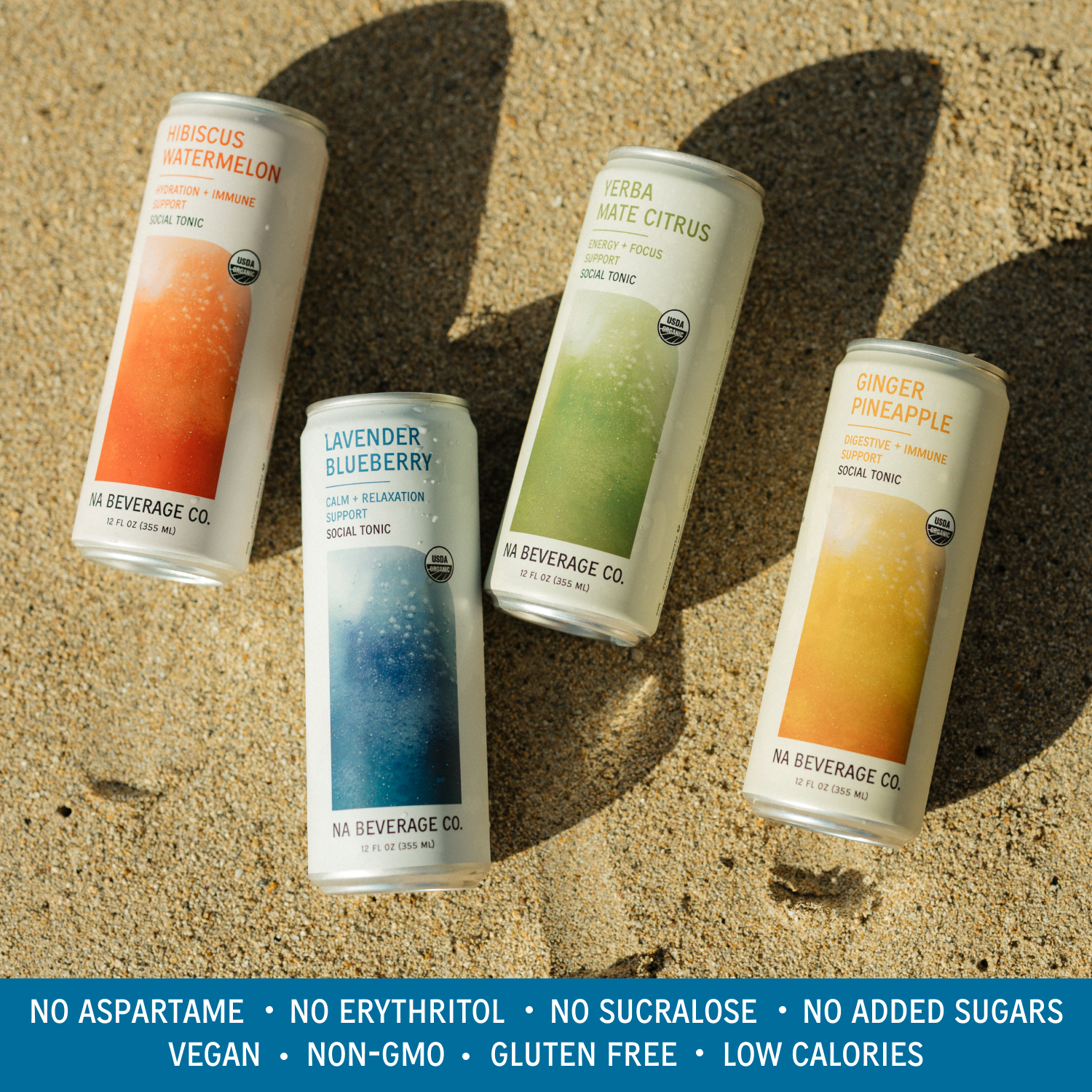 Four cans of NA Beverage Co. on a sandy background